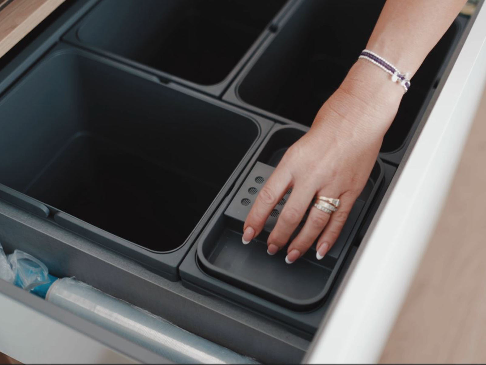 Slide-and-hide kitchen bin lids demonstrated by the homeowner