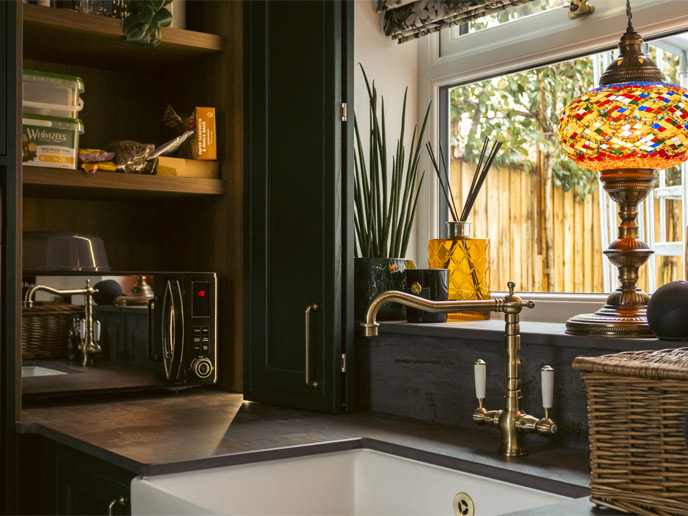A Belfast sink amidst dark green in-frame utility room cabinets