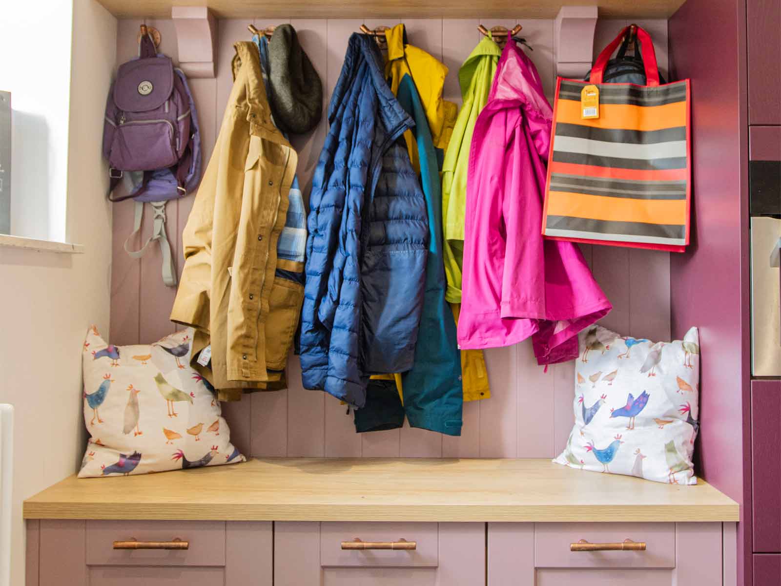 A pink boot room and larder comprising multi-colour kitchen cabinets