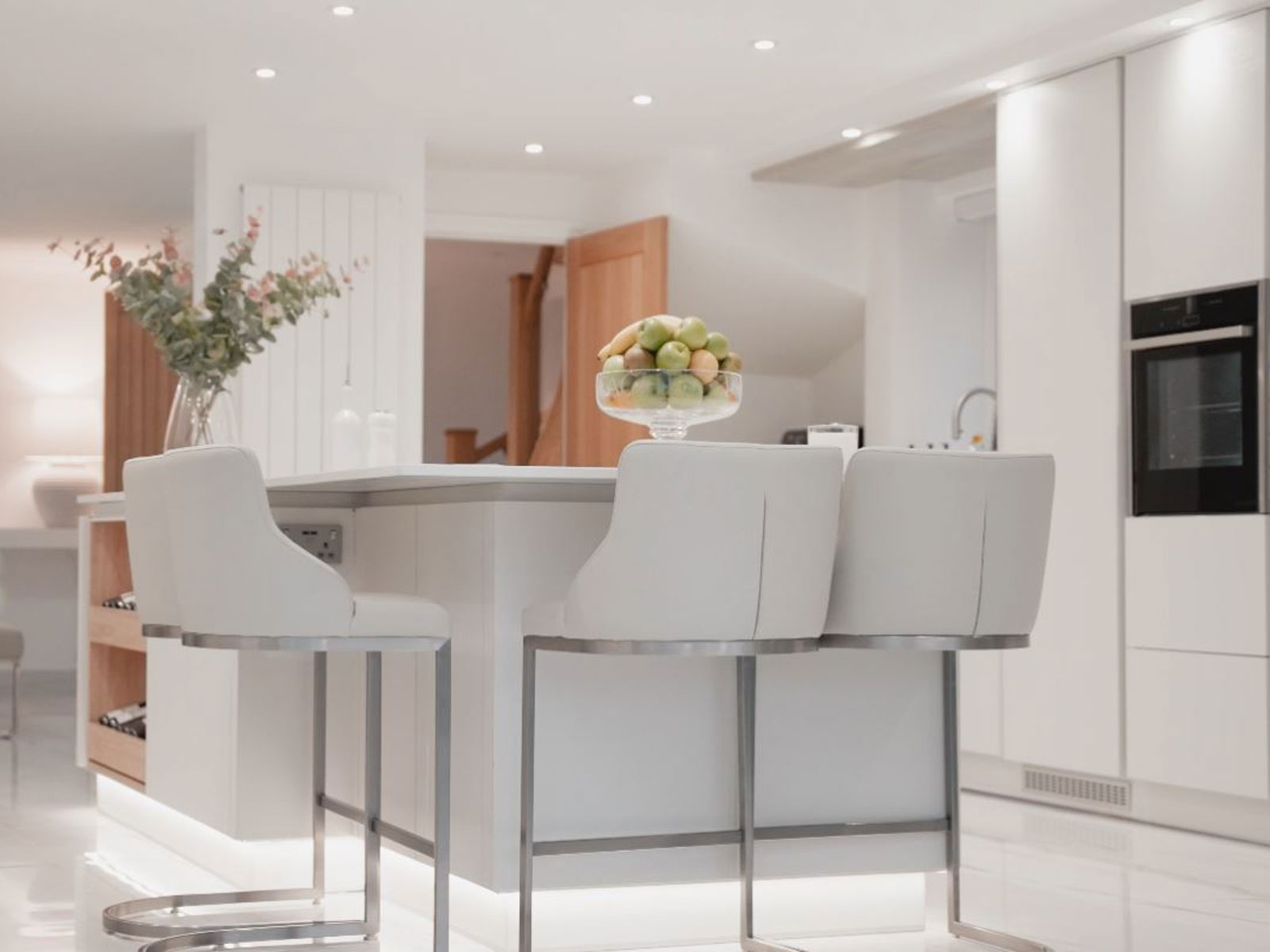 A white handleless kitchen island with concealed kitchen storage capacity