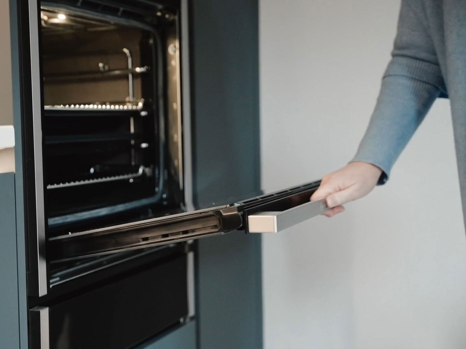 A Neff hide and slide oven, demonstrated by Lisa in her grey handleless kitchen