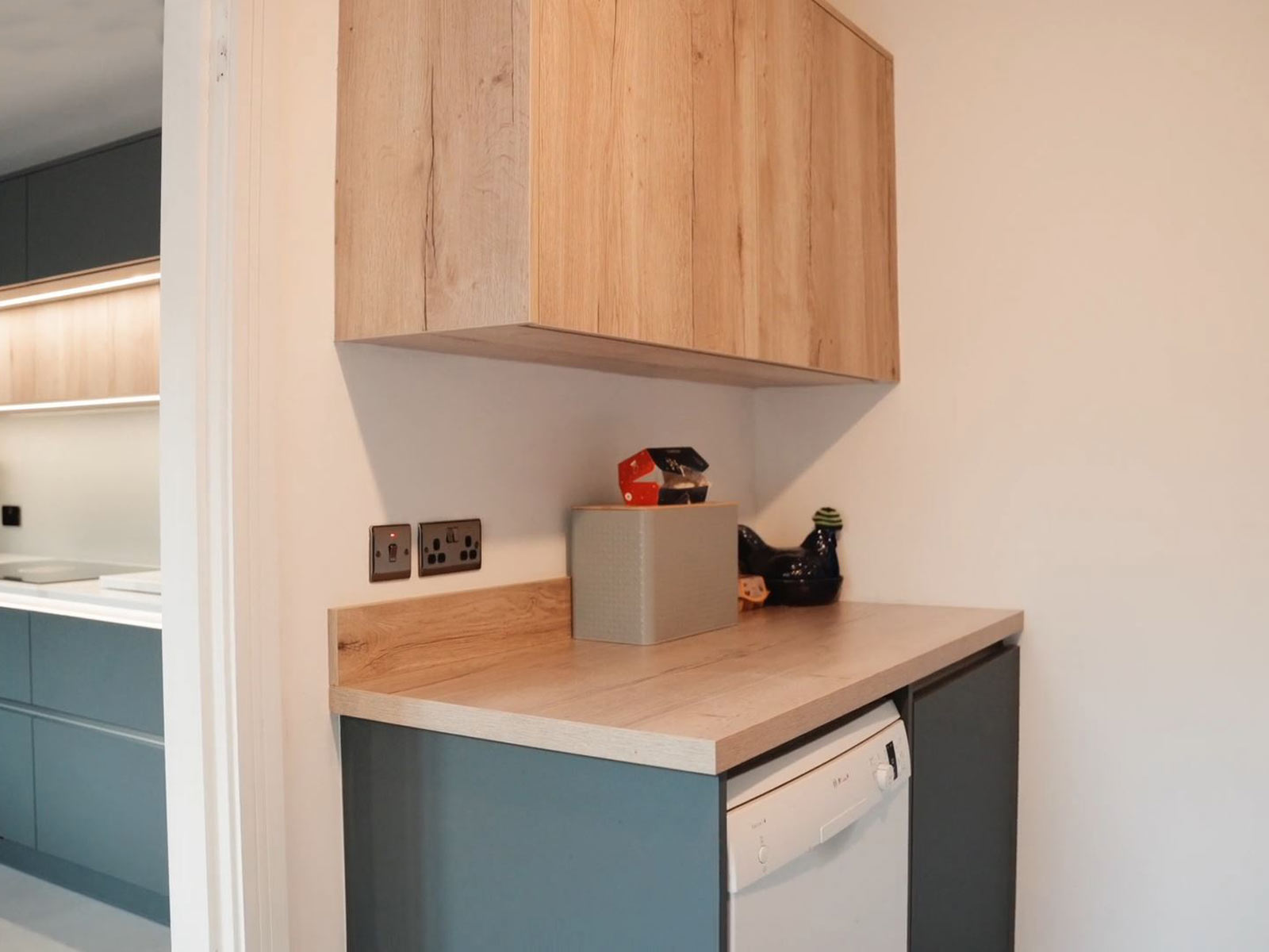 A utility room counter used as a kitchen work surface alongside wall cupboards