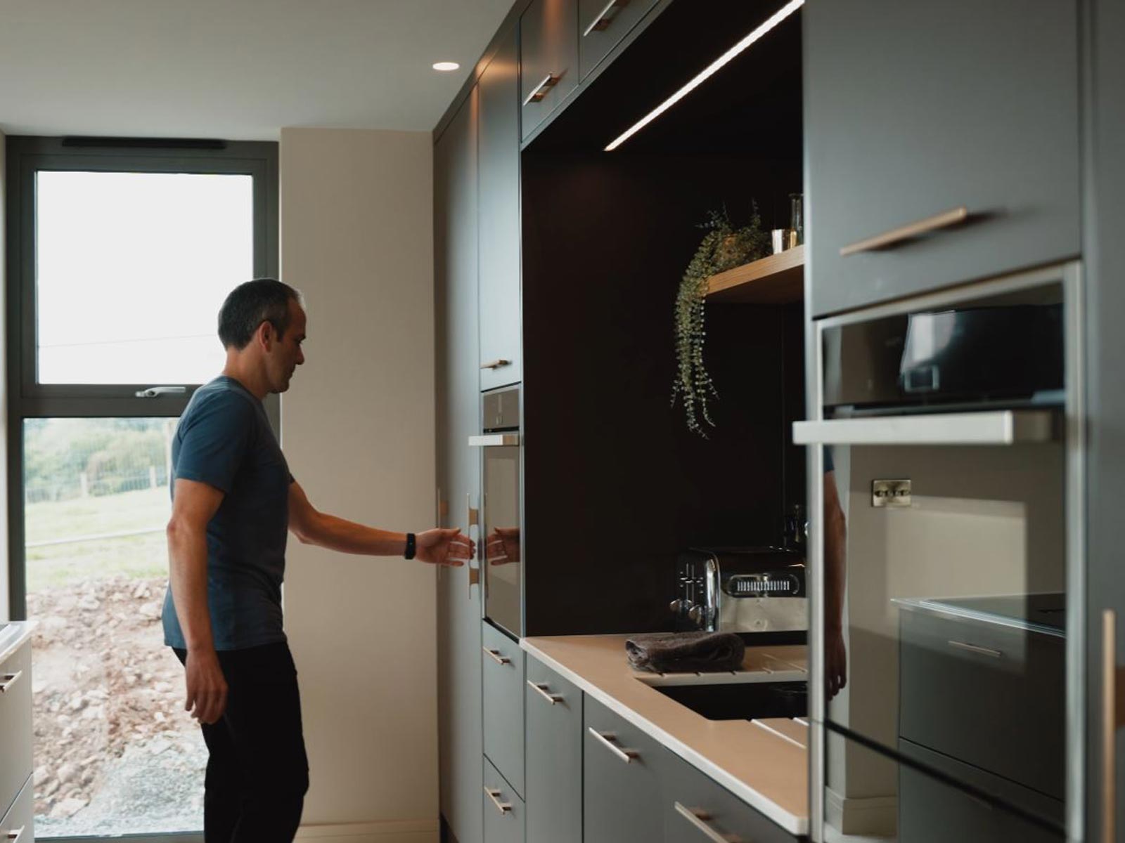 Fitted kitchen design features with a man demonstrating how they work